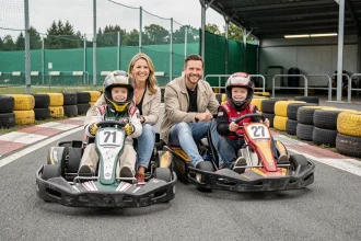 Famille avec deux adolescents en kart sur le circuit Macarthur Miramas, parents souriants en tenue décontractée et enfants en casque de sécurité